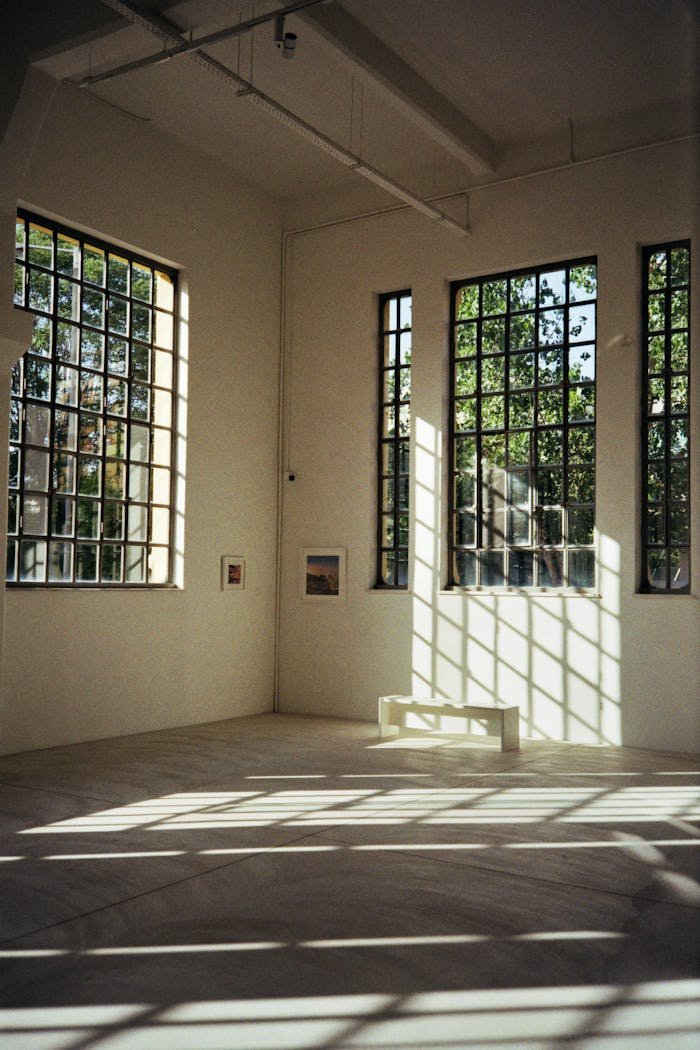 A spacious renovated gallery in Athens with large windows casting sunlight.